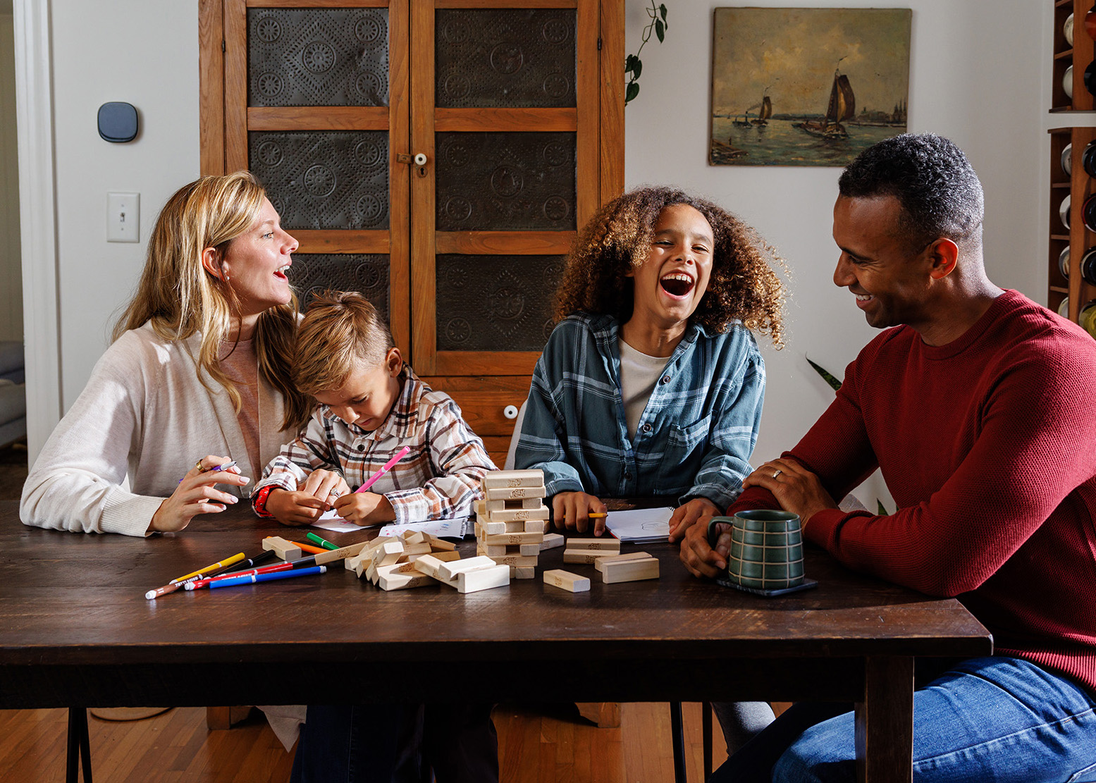 Family laughing and playing Jenga, enjoying the comfort of their smart thermostat-controlled home.