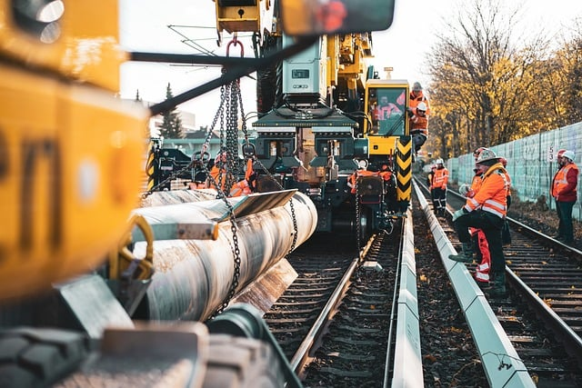 Construction workers in orange safety gear are diligently repairing the train tracks, vital components of public infrastructure.