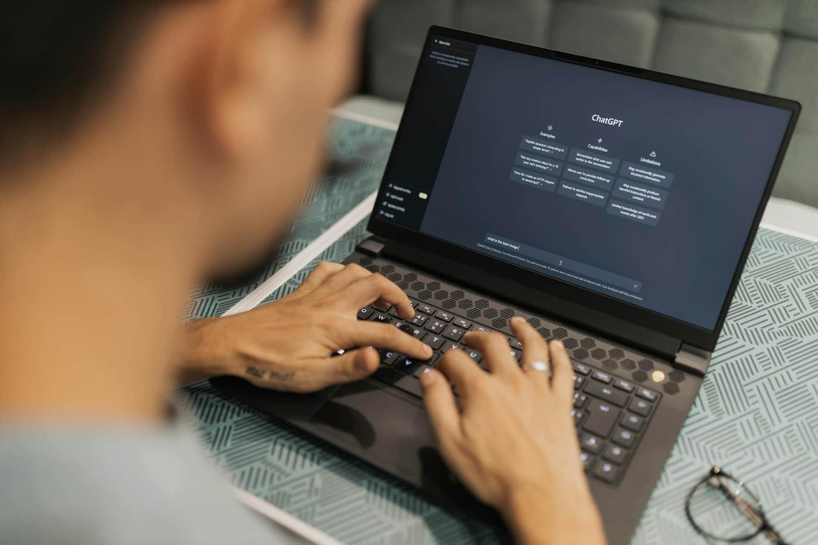 Person typing on a laptop displaying a chatbot interface.