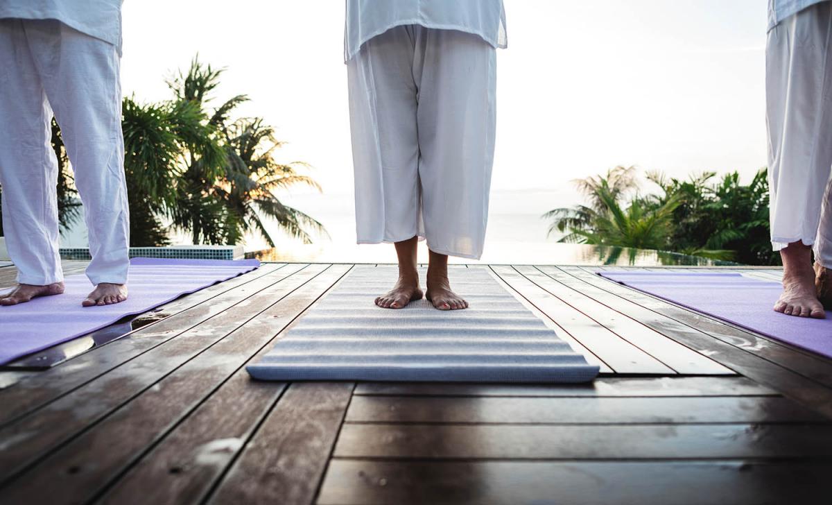 The feet of three people on their yoga mats