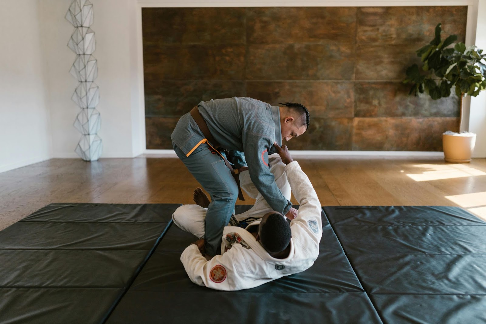 A martial arts instructor teaching a student grappling techniques on the ground