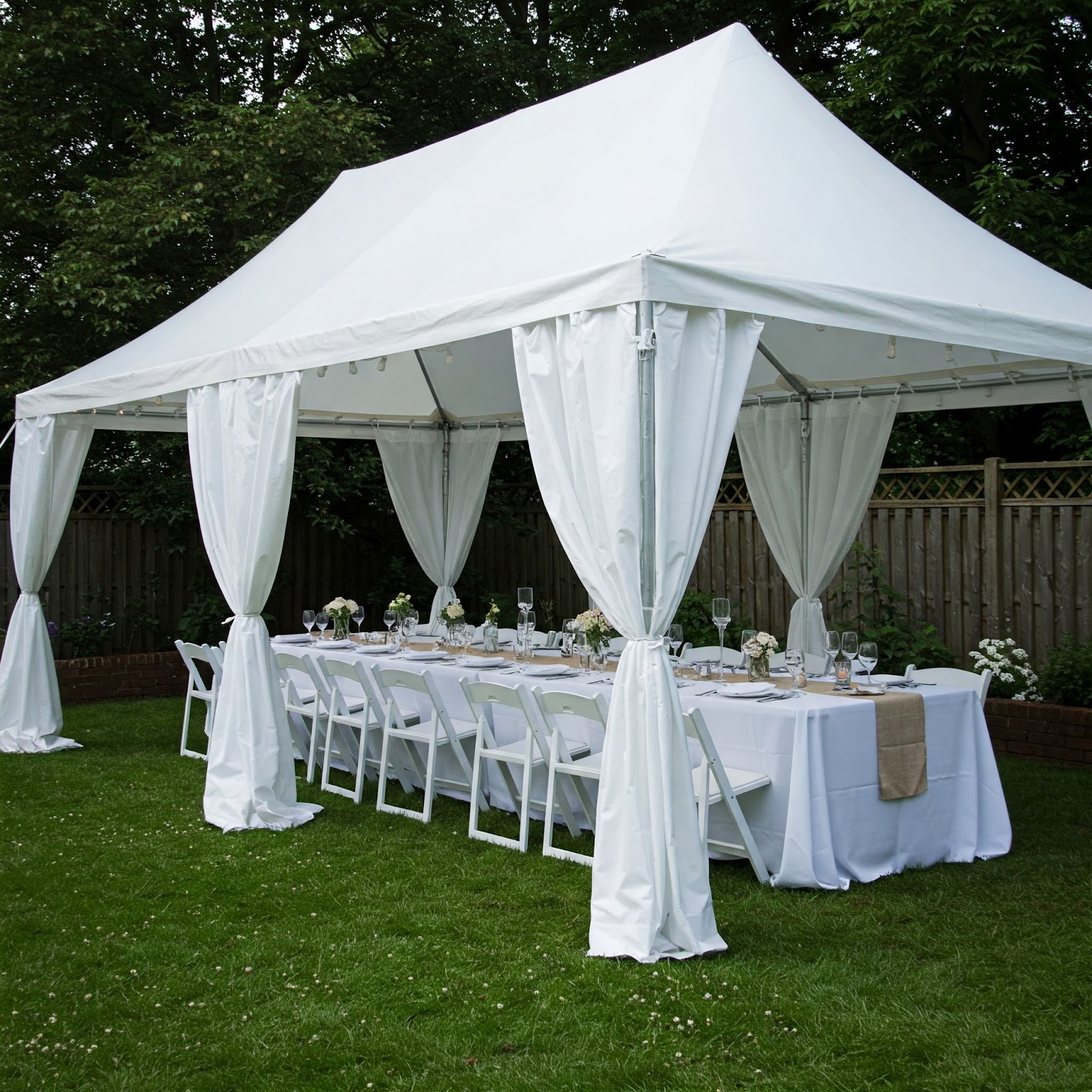 An all-white dining arrangement outdoor with a white canopy.