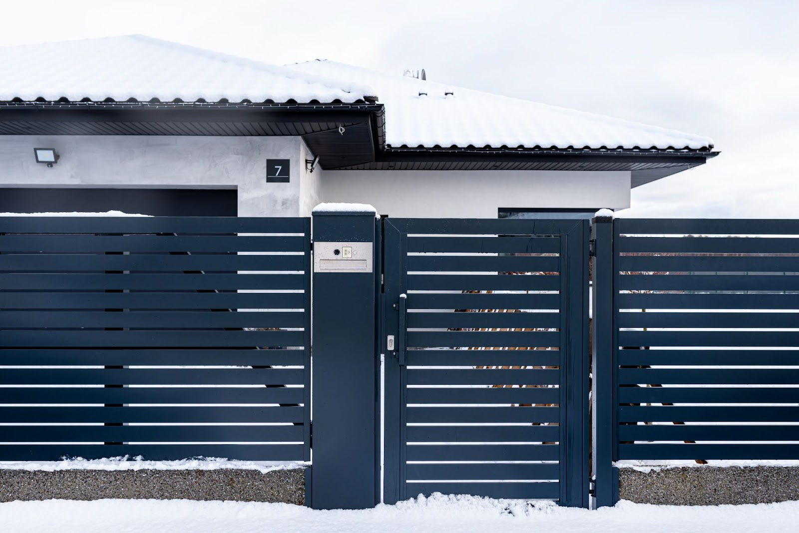 Steel fence in front of a home with snow on the ground. 