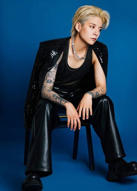 This  contain an image of Amber Liu sitting in a chair with tattoos on their arms and legs, wearing black leather pants