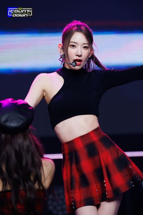 This contains an image of  Sakura wearing a mini skirt and a crop top with bone mic singing on stage