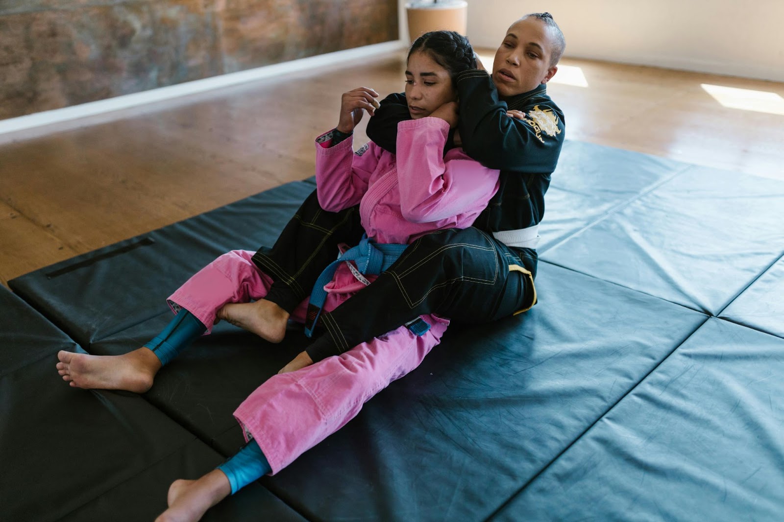 Two martial arts students bpracticing rear chokeholds on the ground