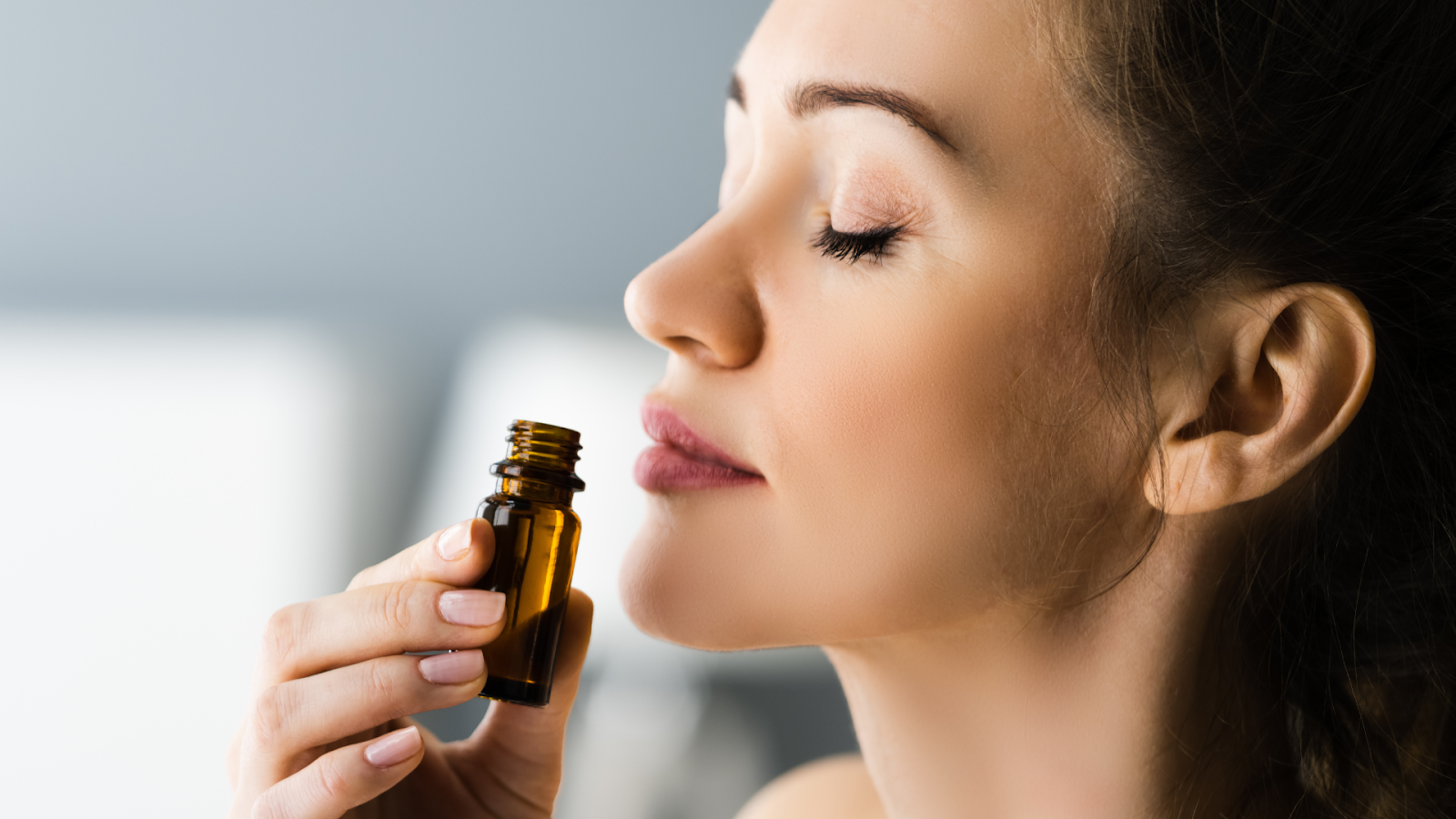 Seorang perempuan sedang mencium botol berisi wewangian/Sumber: Canva