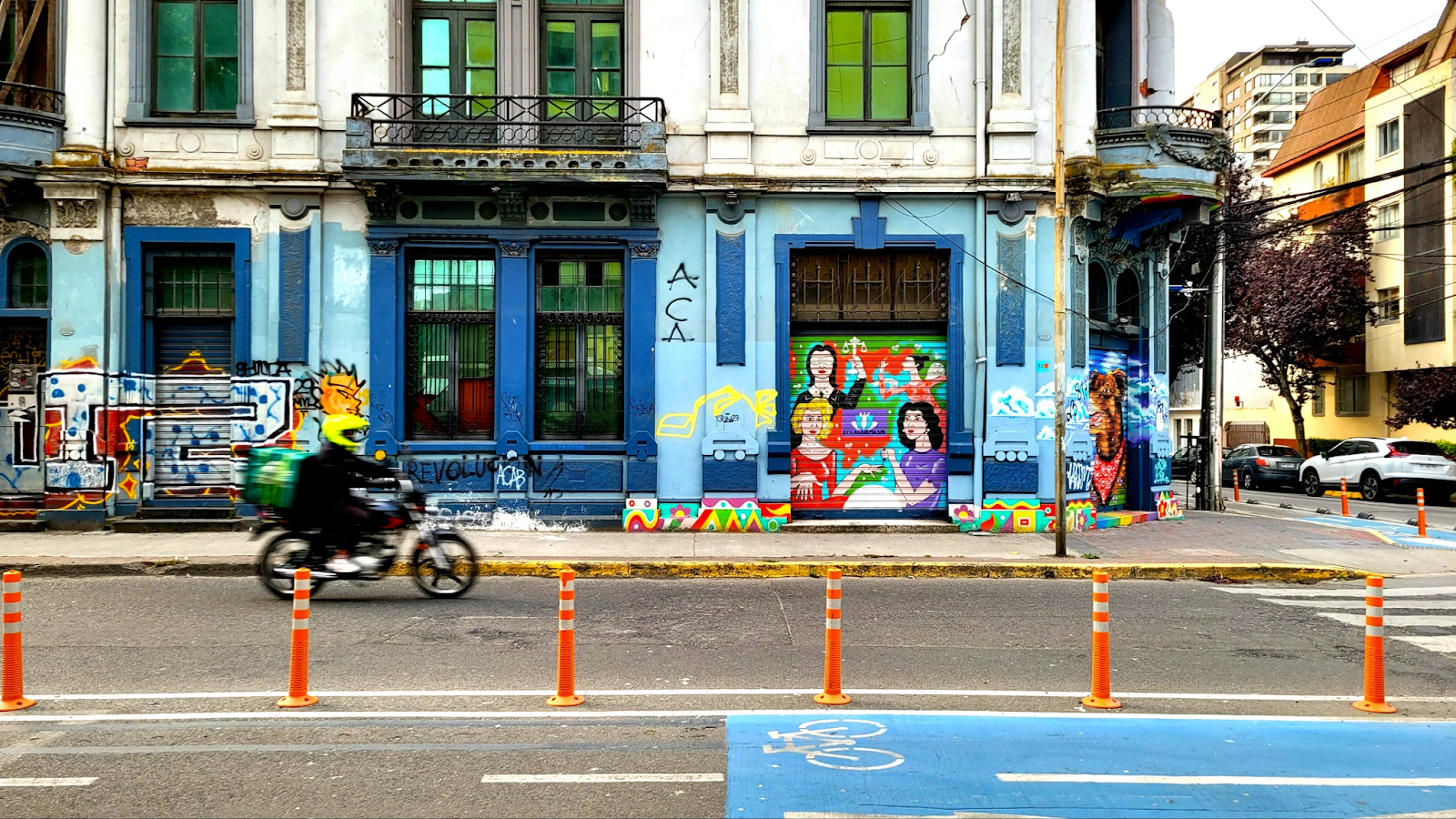 A person on a motorbike with a graffiti wall on the background
