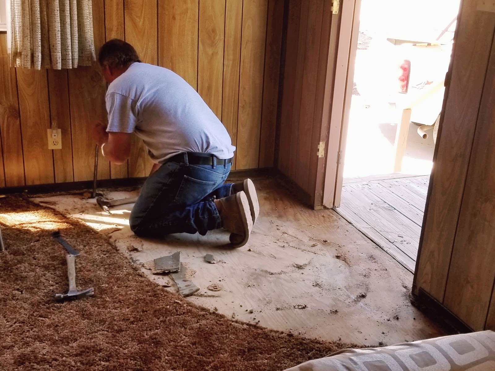 A worker on his knees repairing wood from termite damage.