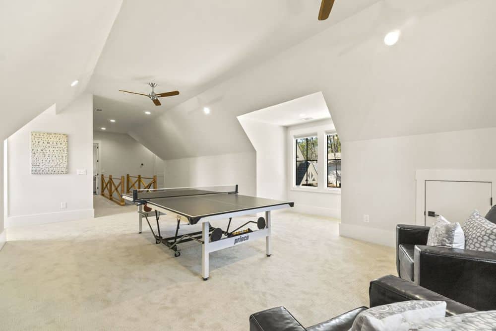 Recreation room with black leather armchairs and ping-pong table over carpet flooring.