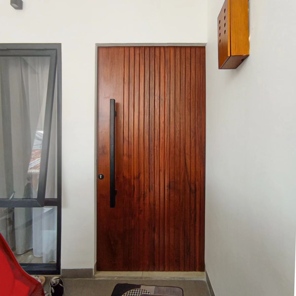 Pintu kayu solid dengan aksen alur garis vertikal yang tegas, memberikan ilusi tinggi dan elegan.