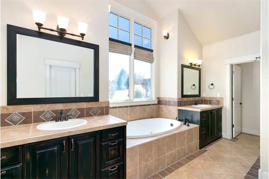 The primary bathroom features his and her sink vanities flanking the drop-in bathtub.