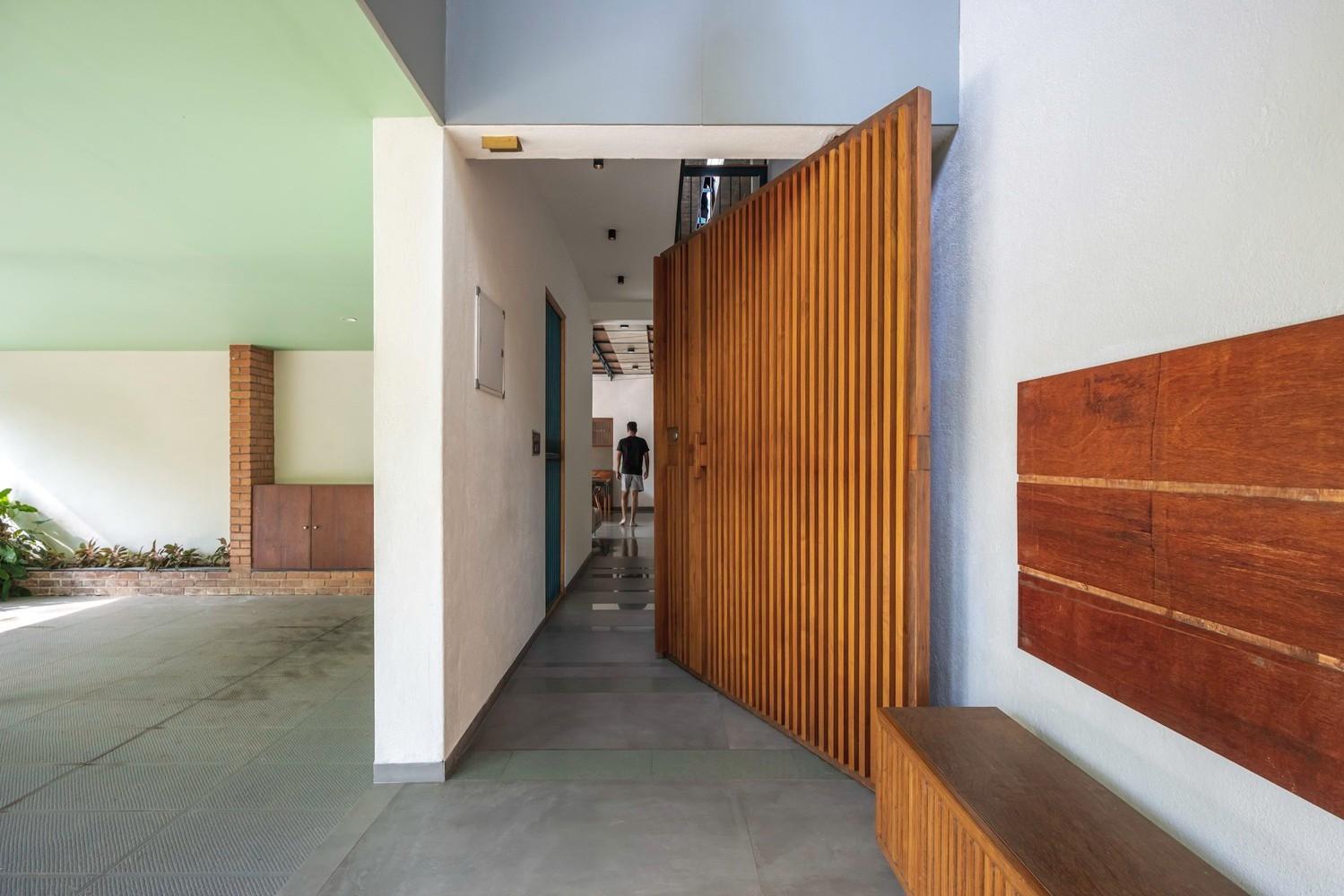 A modern entryway, perfect for architectural photography, features a large wooden door with vertical slats, partially open to reveal a hallway inside.