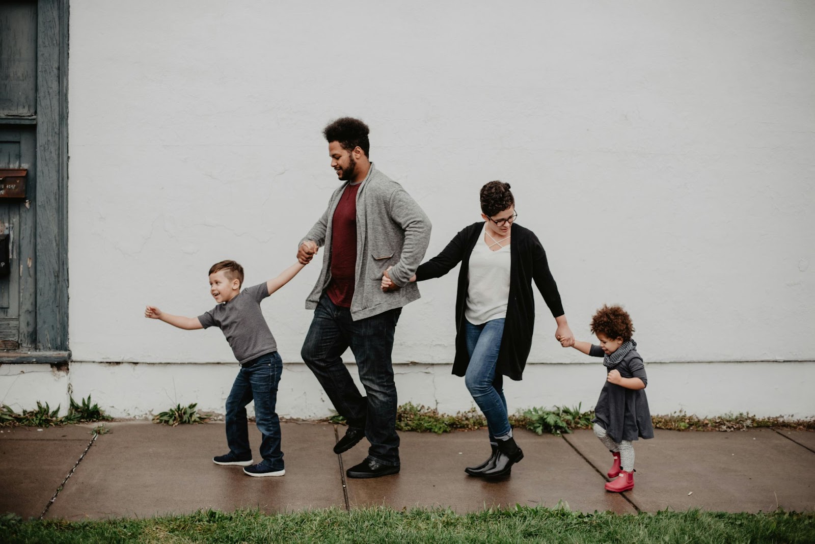 Two parents holding hands with their two children as they walk 