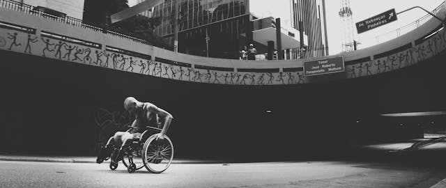 A person in a wheelchair moves through an underpass in a city, designed by architects to enhance community development.