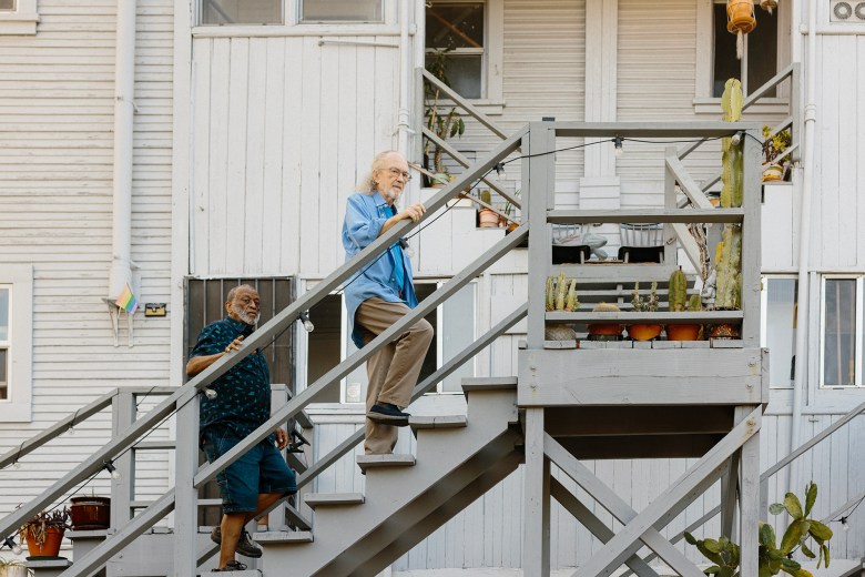 Osbey Jackson and husband Luke Johnson walk up the exterior stairs of their home towards a small patio. Various plants sit in pots on the patio and stairs.