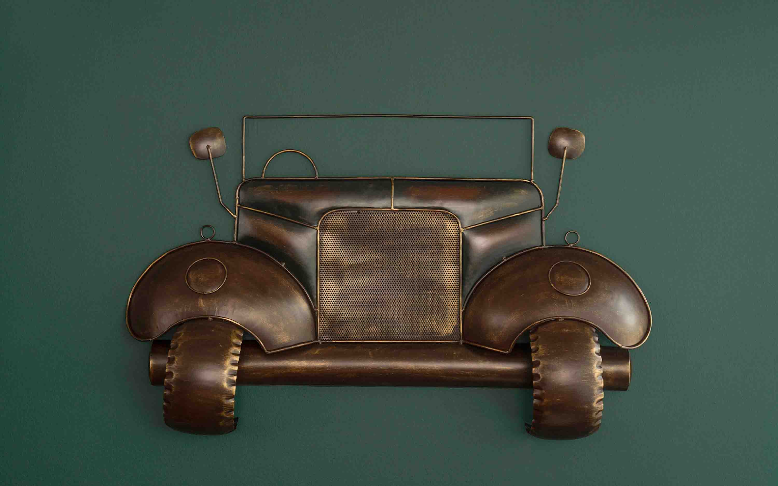 Wall-mounted vintage car art sculpture made of metal with a rustic bronze finish,&nbsp; displayed against a dark green background.