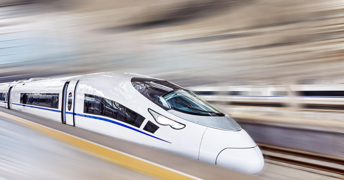 A high-speed bullet train in China speeding through a station, showcasing its aerodynamic design and sleek white exterior with blue accents.