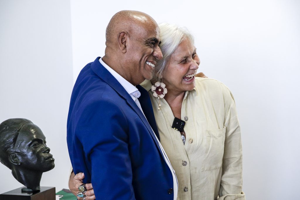 Fotografia registra o reitor da UFPA Gilmar Pereira da Silva  e a cantora Fafá de Belém em momento de descontração. Os dois estão abraçados e sorriem, 