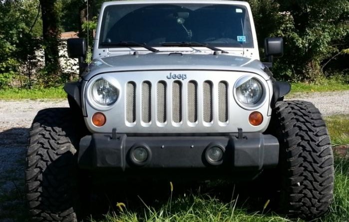 Front view of a Jeep with tires sticking out past the fenders, emphasizing legal and safety aspects of tire protrusion.