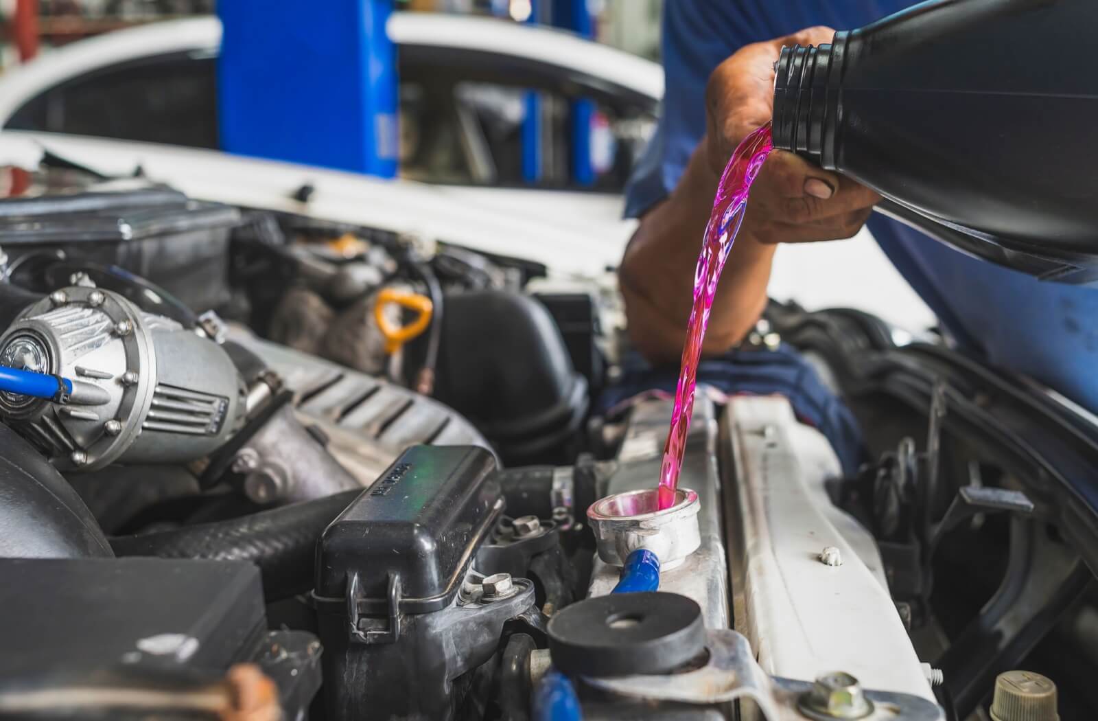 A close-up image of a person filling a radiator with pre-mixed coolant to ensure it remains in its optimal cooling temperature range.