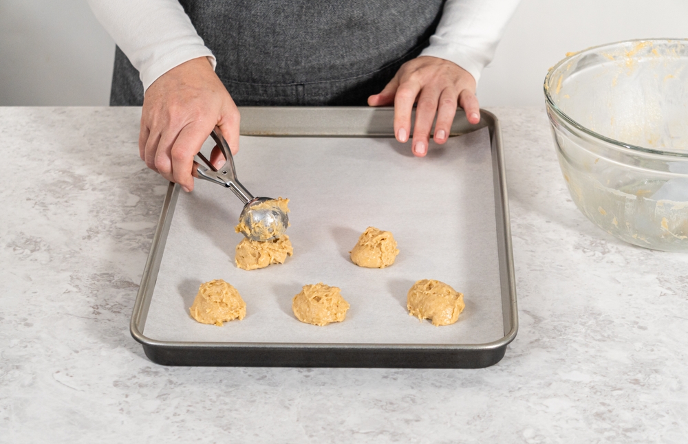 Woman scooping cookie dough on a baking sheet to freeze