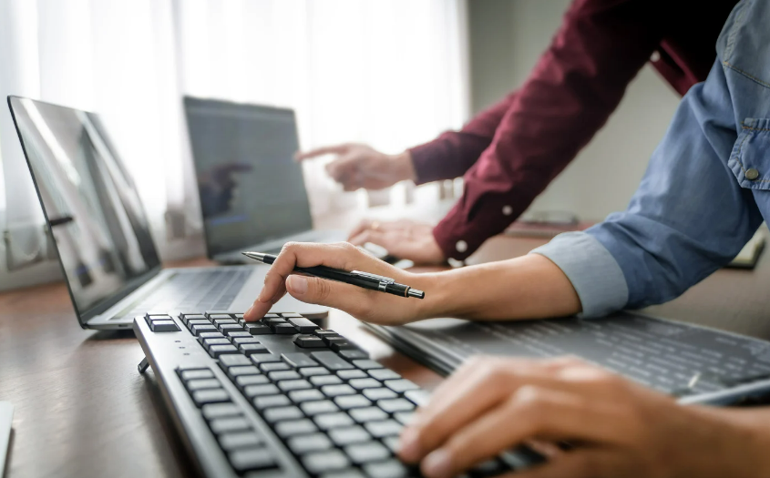 Two office staff collaborating on software platform together