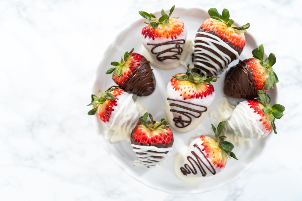 Dark and white chocolate-covered strawberries sitting on a tray at room temperature