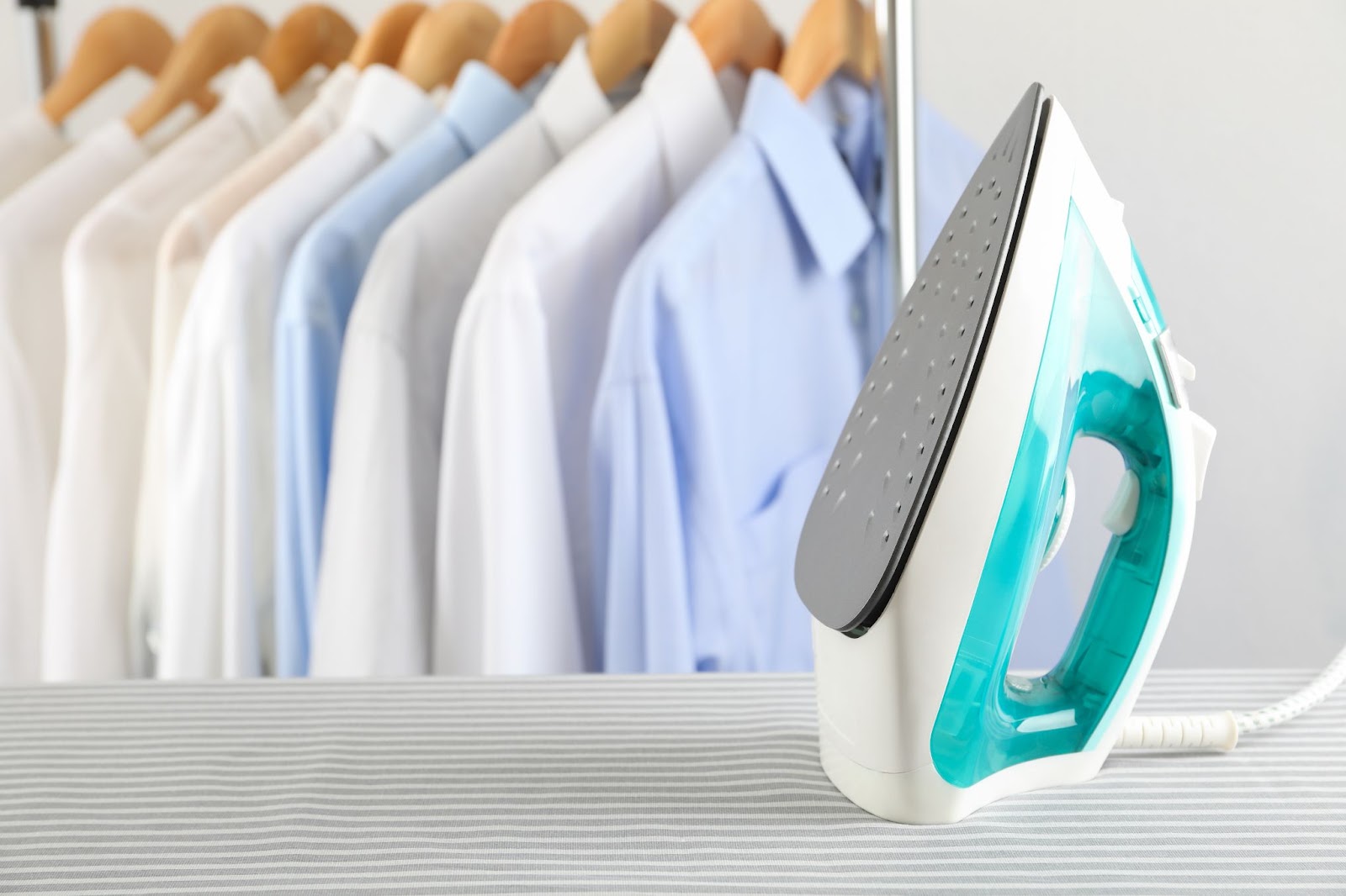 Clothing iron next to hanging button down shirts