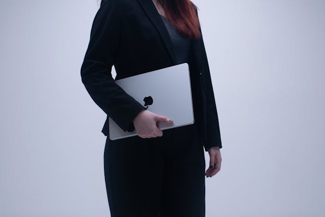 A professional woman holding a laptop in office attire-women in tech
