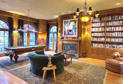 A luxurious room with a pool table, comfortable seating and a bookshelf with art on the walls.