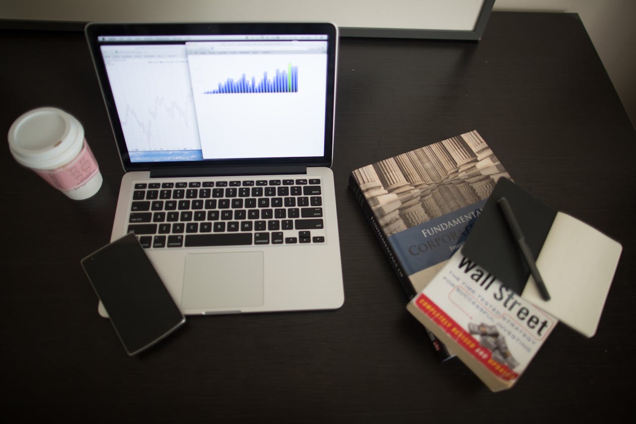 Image of a laptop on the table with notebook, books and coffee