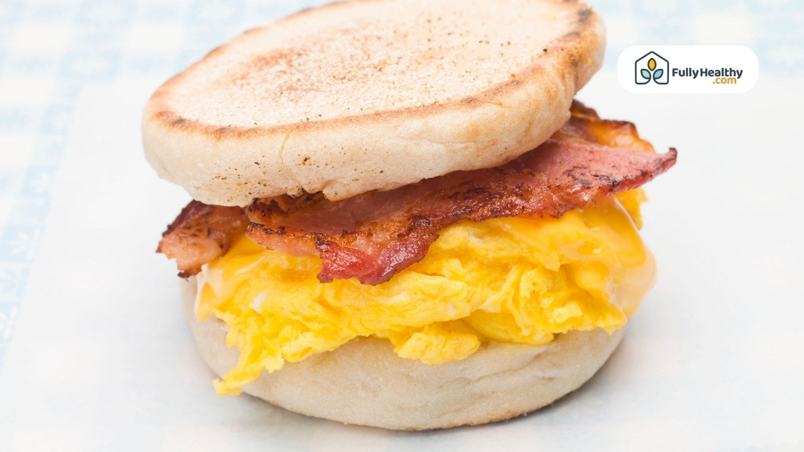 English muffin sandwich with scrambled eggs bacon and melted cheese