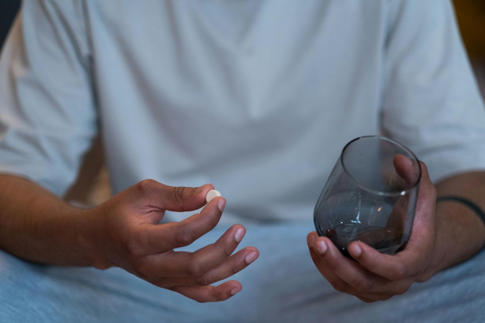 Man holding a prescription pill and a glass of water