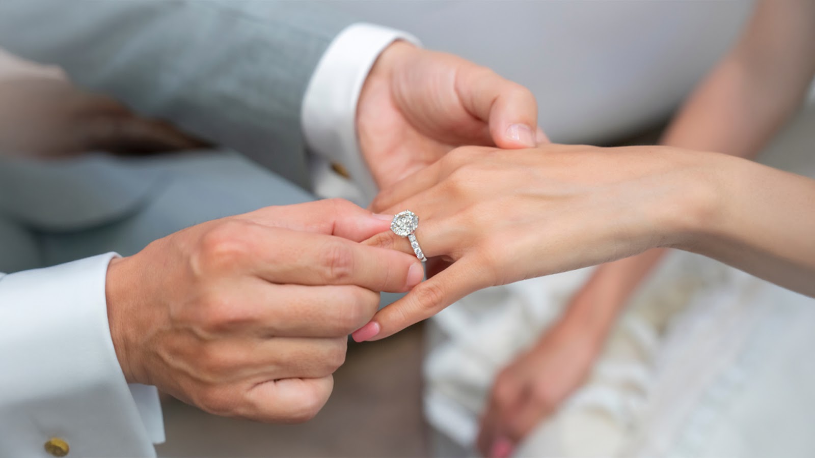 A man is sliding a wedding ring onto a woman's finger, symbolizing their commitment to each other.