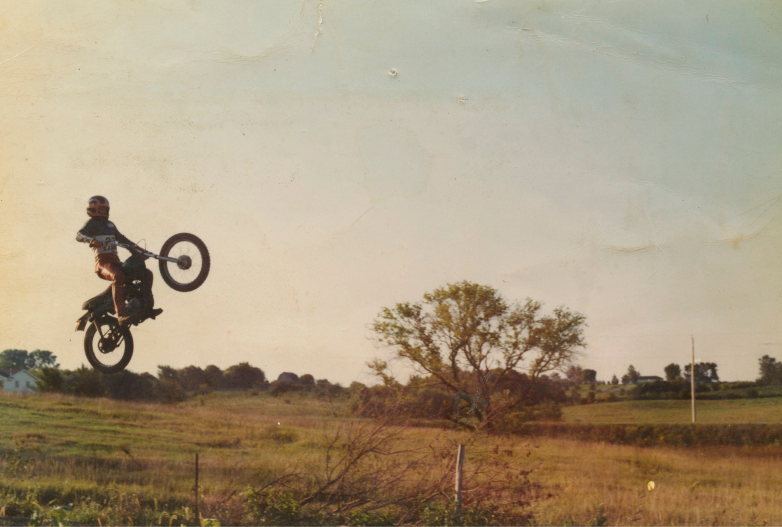 A man riding a motorcycle goes up on the back wheel on the left side of the image. 