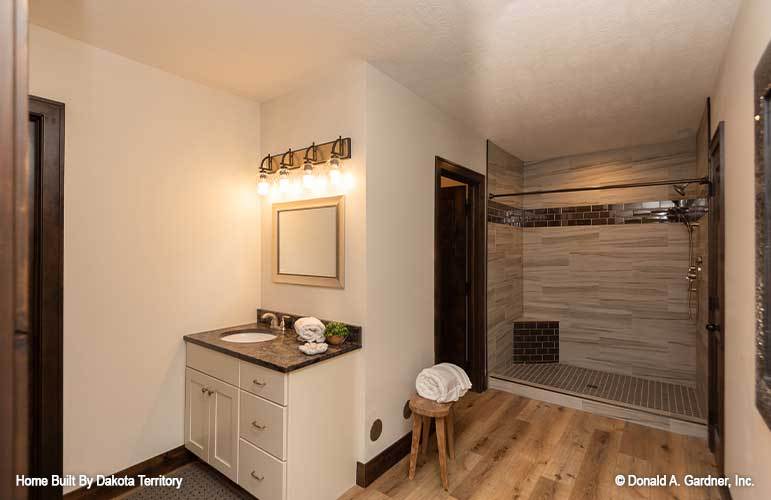 The bathroom includes a toilet room concealed by the dark wood door.