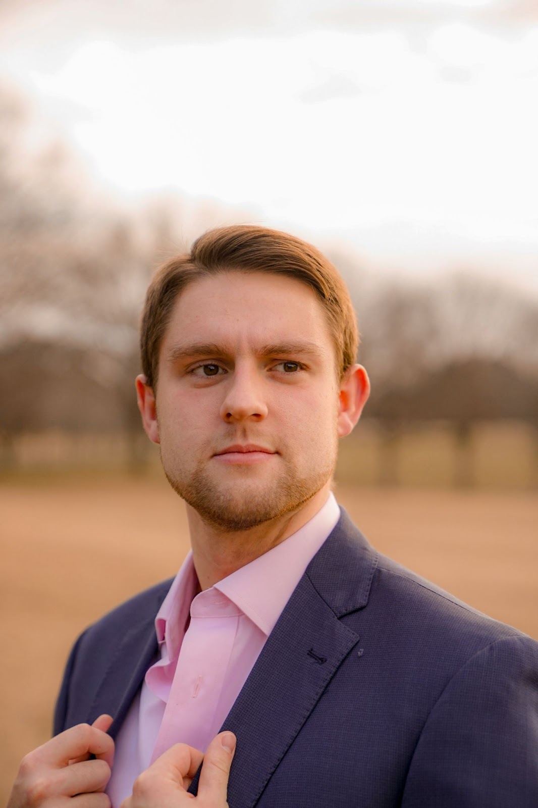 A man standing in an outdoor setting posing for his professional headshot