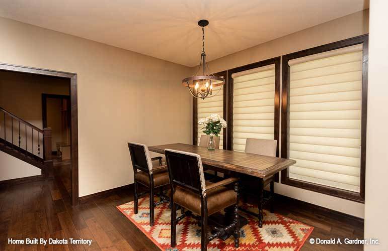 Dining area with an iron chandelier and rectangular dining set sitting on a patterned area rug.