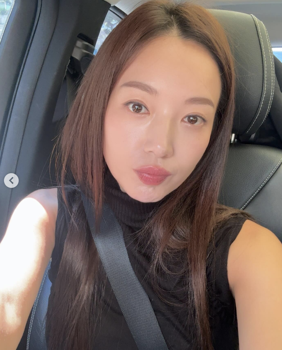 A picture of Kim Min Kyung wearing a black dress sitting in a car