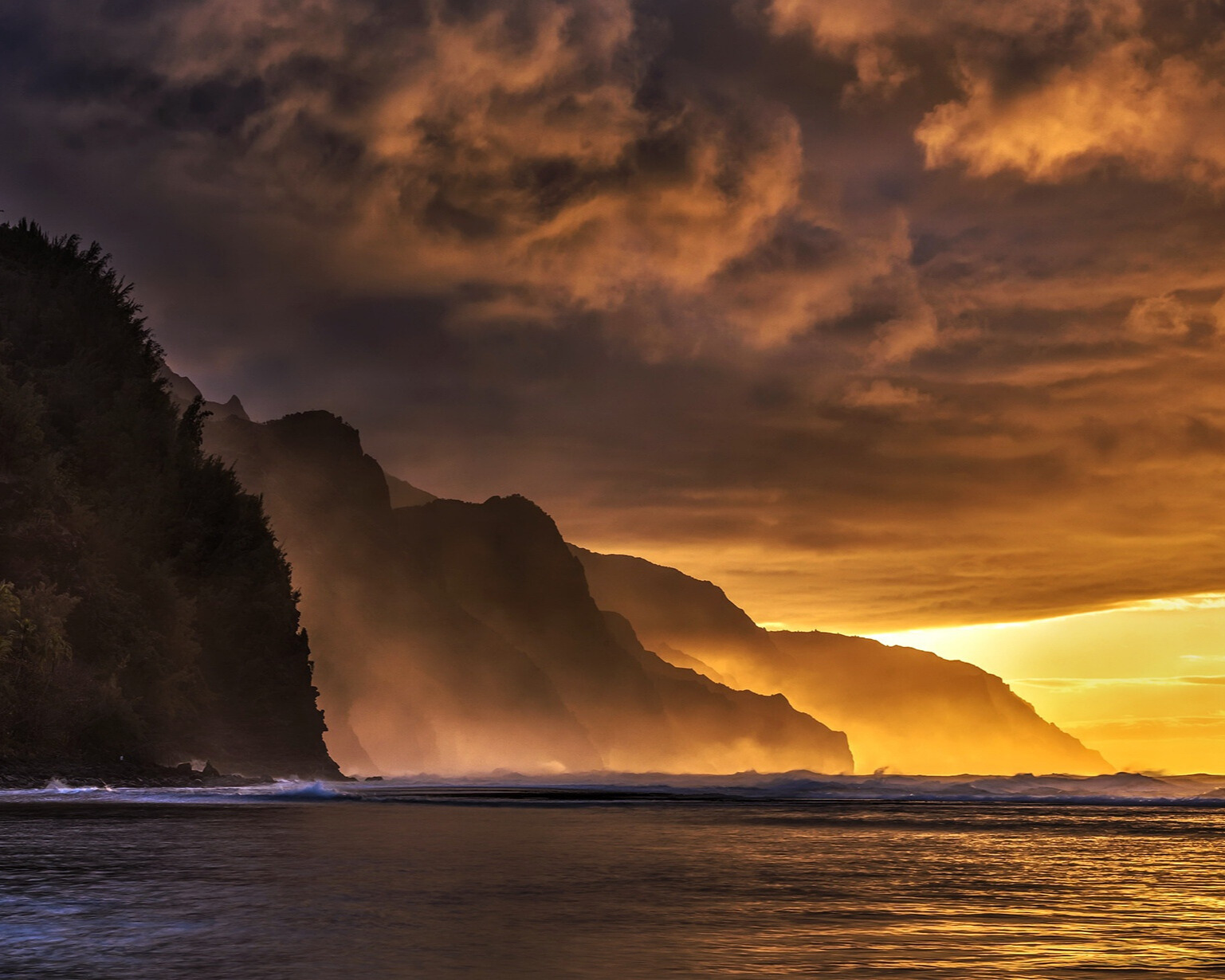 Hazy mountains with dark and orange hues in the sky.