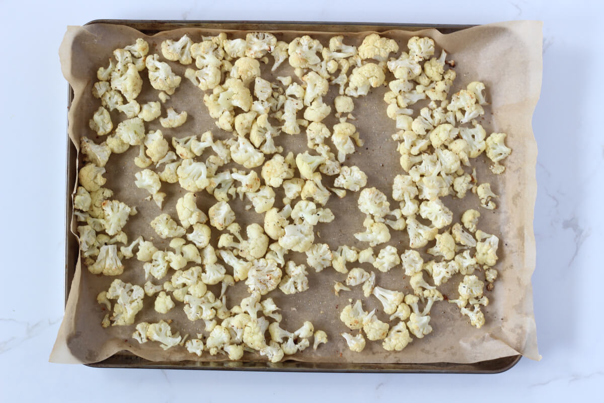 Roasted cauliflower pieces on baking sheet