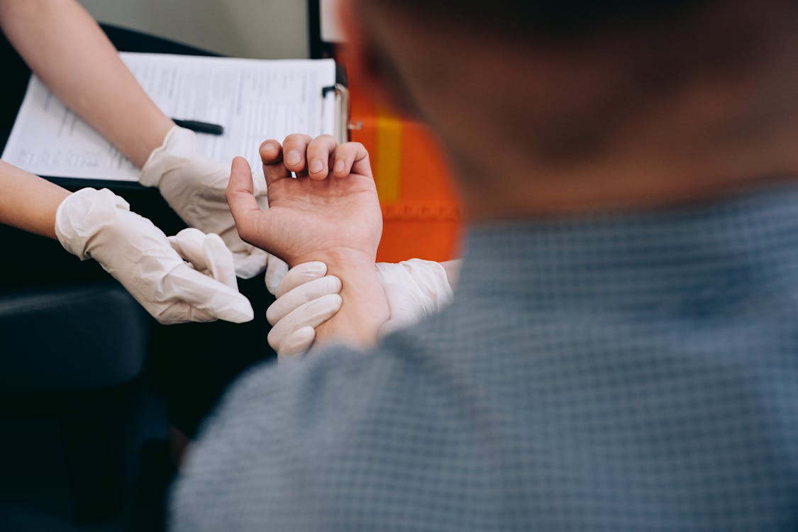 Free Healthcare professional checks man's pulse during medical examination. Stock Photo