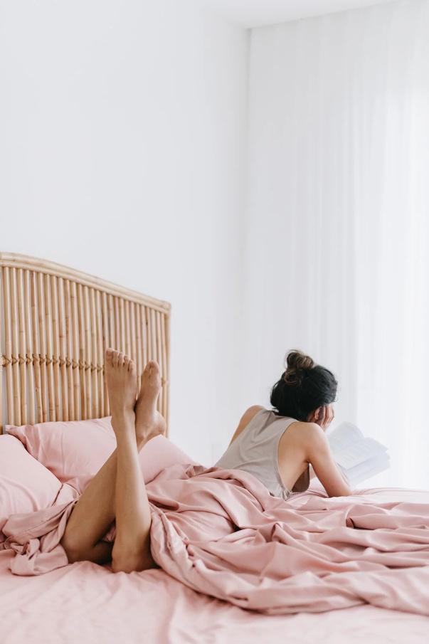 A person lying on a bed reading a bookDescription automatically generated