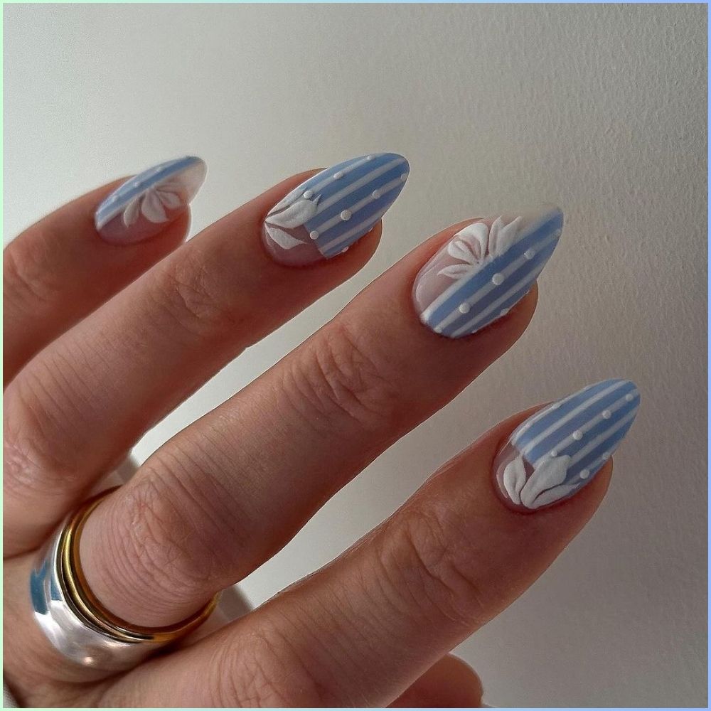 Close up of hands with flowered designed blue nails having White polka dots adorn the stripes