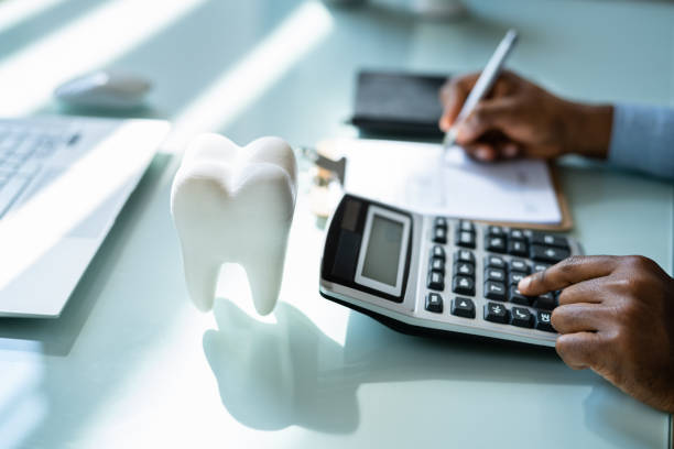 An image of a ceramic tooth, calculator and notepad in a dentist’s office. 