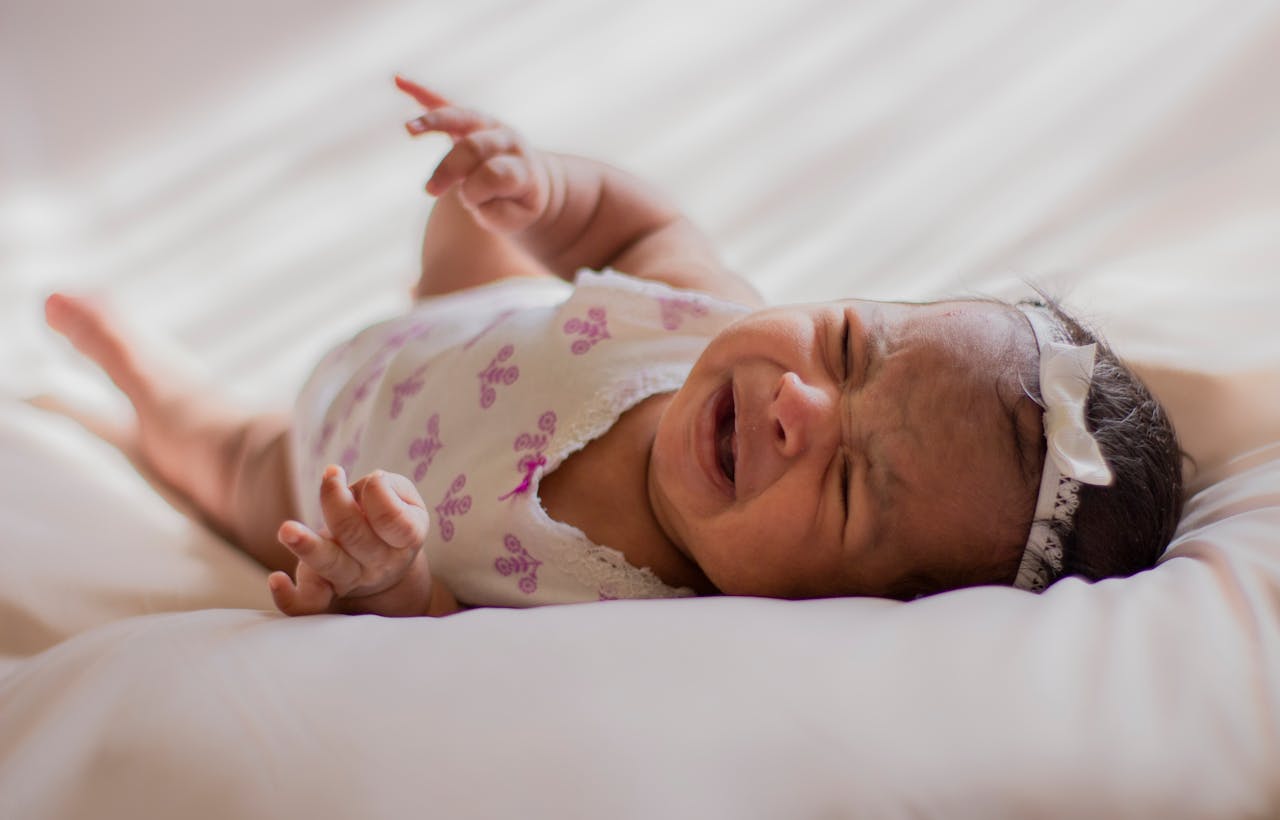 Baby In A Onesie Lying On Bed // Healthier Baby Today