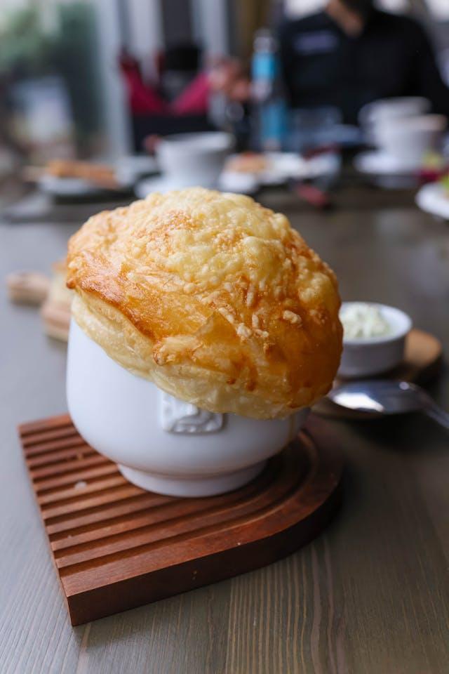 A white cup with a puffy crust on top

Description automatically generated