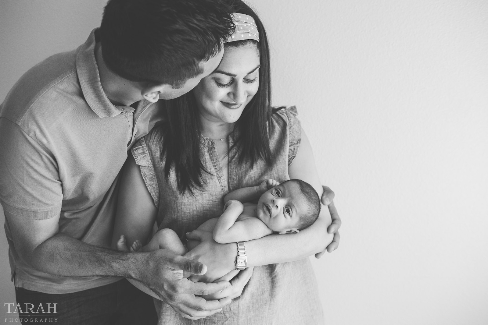 Family in black and white theme, gazing lovingly at their baby, capturing a timeless moment.