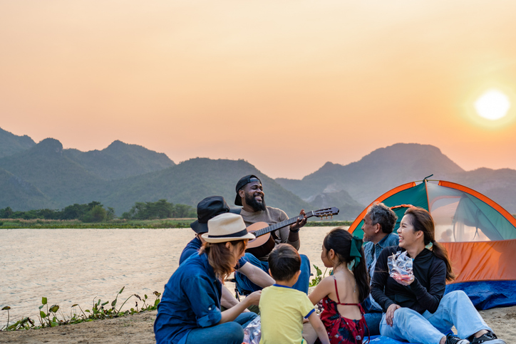 A group of friends and family enjoying a sunset by a lake as they camp. 